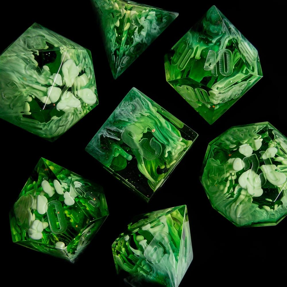 Green resin dice with white flowers cast inside, on black